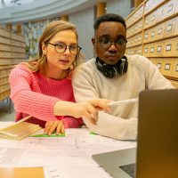 two people working on a laptop in a library Dimensions 1000 × 1500